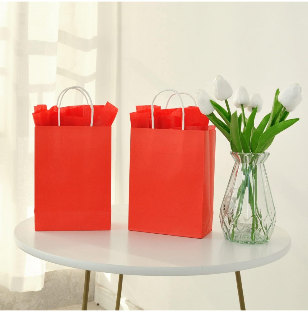 trois sacs en papier kraft rouge posés sur une étagère de boutique