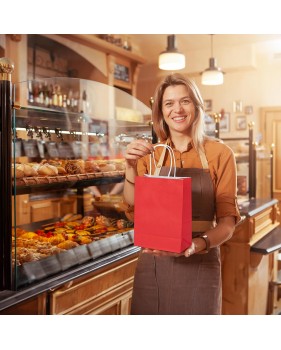 commerçante remettant un sac en papier kraft rouge dans sa boutique