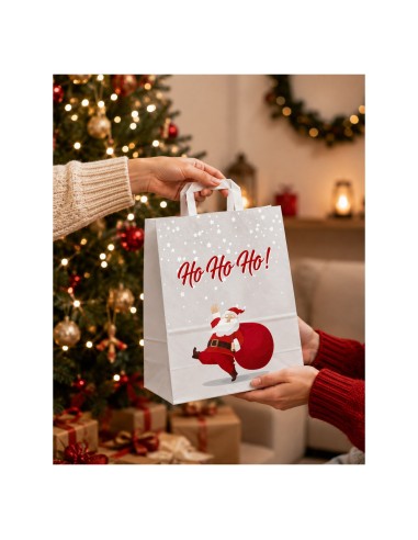 Sac cadeau kraft Père Noël remis à une cliente devant un sapin décoré