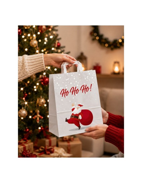 Sac cadeau kraft Père Noël remis à une cliente devant un sapin décoré