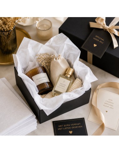 Zwarte geschenkdoos gevuld met wit zijdepapier, geurkaars en interieurparfum