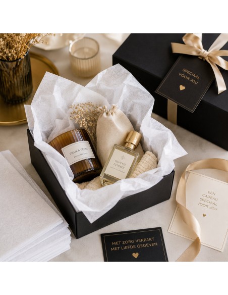 Zwarte geschenkdoos gevuld met wit zijdepapier, geurkaars en interieurparfum