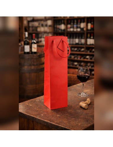 Sac papier bouteille rouge 10+9x39 cm à poignées cordelettes sur un comptoir de cave à vin