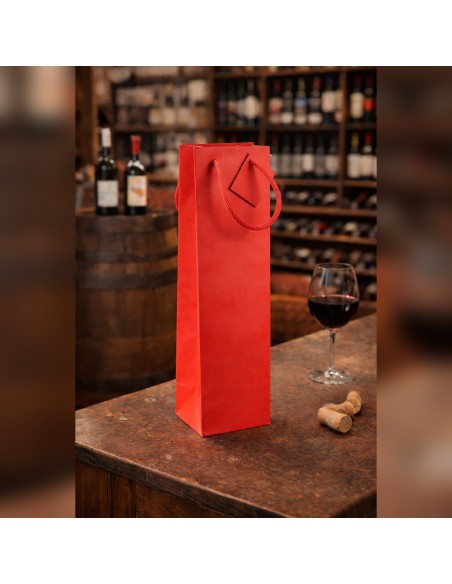 Sac papier bouteille rouge 10+9x39 cm à poignées cordelettes sur un comptoir de cave à vin