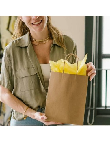 cliente tenant un sac en papier kraft brun garni de papier de soie jaune