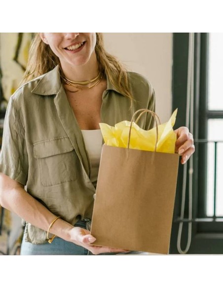 cliente tenant un sac en papier kraft brun garni de papier de soie jaune